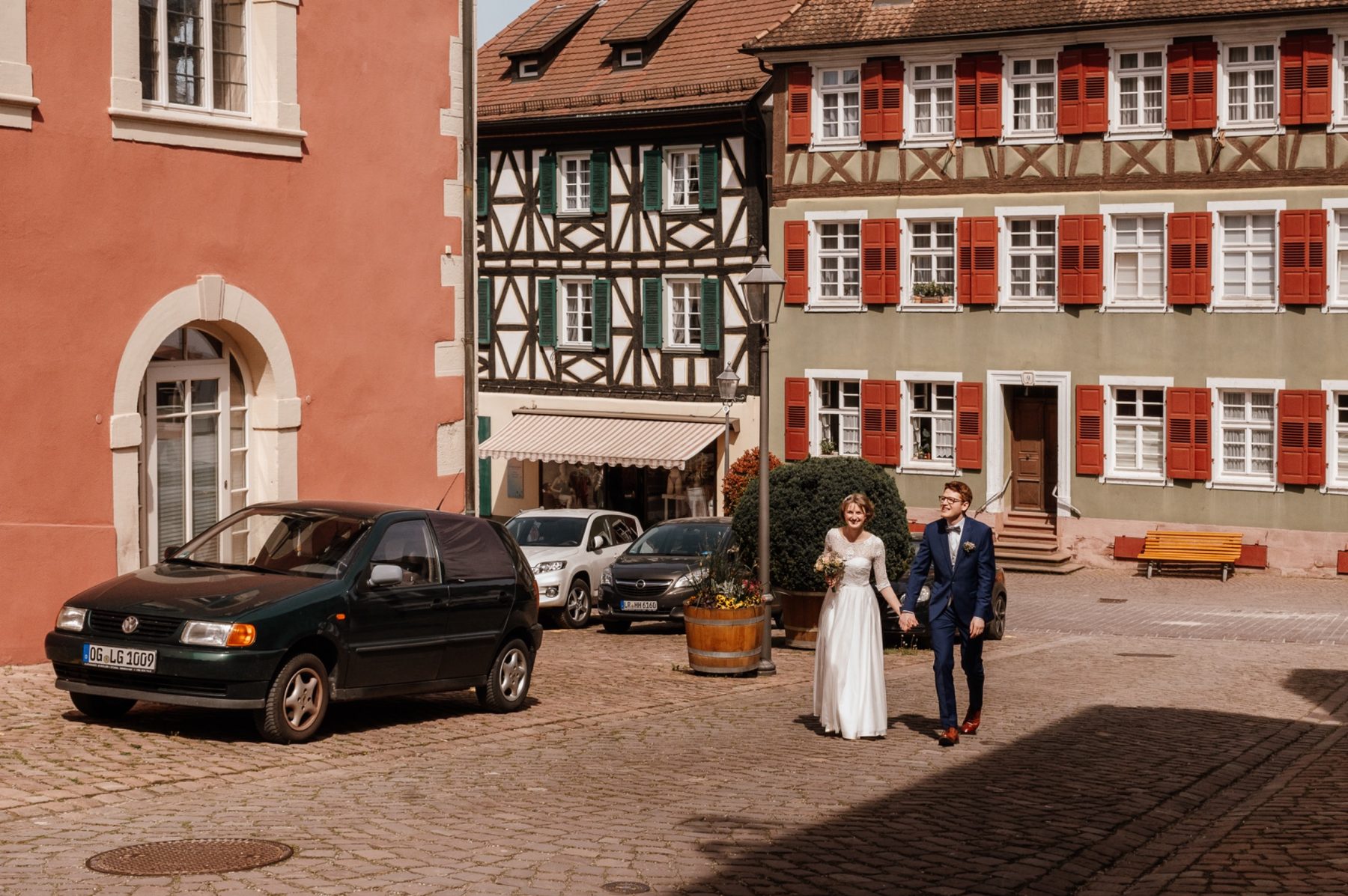 Clara und Andreas spazieren strahlend über den Marktplatz Ettenheim nach ihrer standesamtlichen Trauung