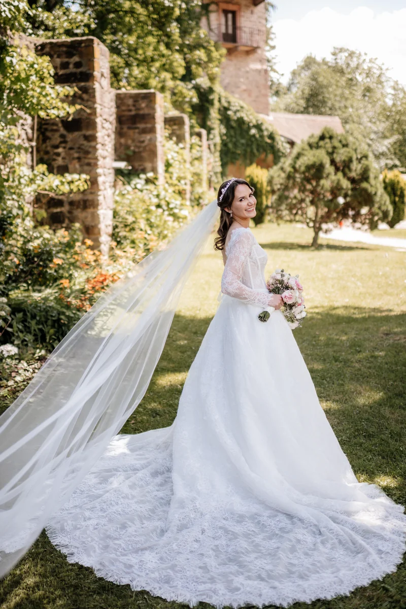 Sandra in ihrem Spitzenkleid mit langem Schleier bei der Hochzeit