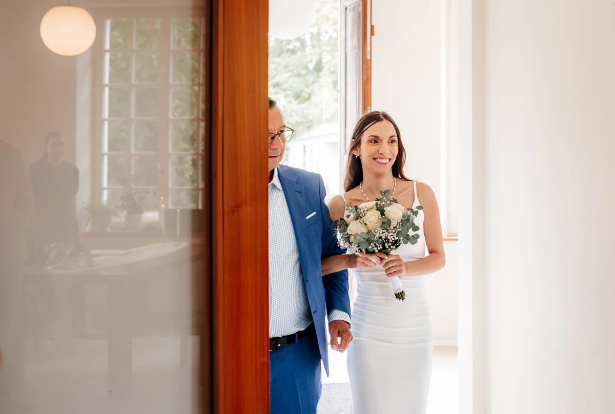 Die Braut mit ihrem Blumenstrauß in der geöffneten Tür