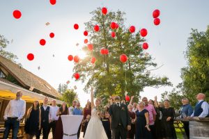 Familie und Gäste lassen rote Luftballons aufsteigen vor dem Haus am Teich in Ettenheim