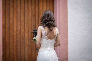 Ein Foto einer Braut, die vor der Tür der Margarethenkapelle in Herbolzheim auf den Beginn ihrer Hochzeit wartet.