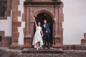 Ein Foto eines Brautpaares vor der Ausgangstür des Standesamts in Freiburg, fotografiert von der Fotografin Isabela Campos.