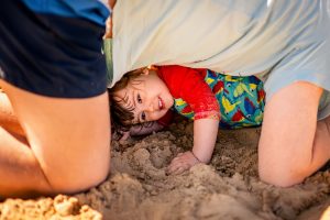 Kind und Papa spielen im Sandstrand und schützen sich vor der Sonne