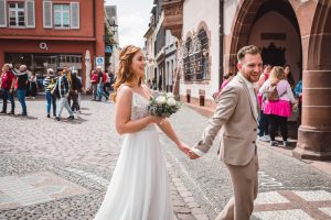 Brautpaar spaziert Hand in Hand durch die Altstadt von Freiburg nach ihrer standesamtlichen Hochzeit im Rathaus