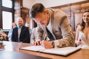 Bräutigam unterzeichnet das Heiratsregister im Rathaus Freiburg