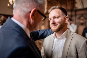 Bräutigam im Gespräch mit älterem Mann bei der Hochzeit im Rathaus in Freiburg