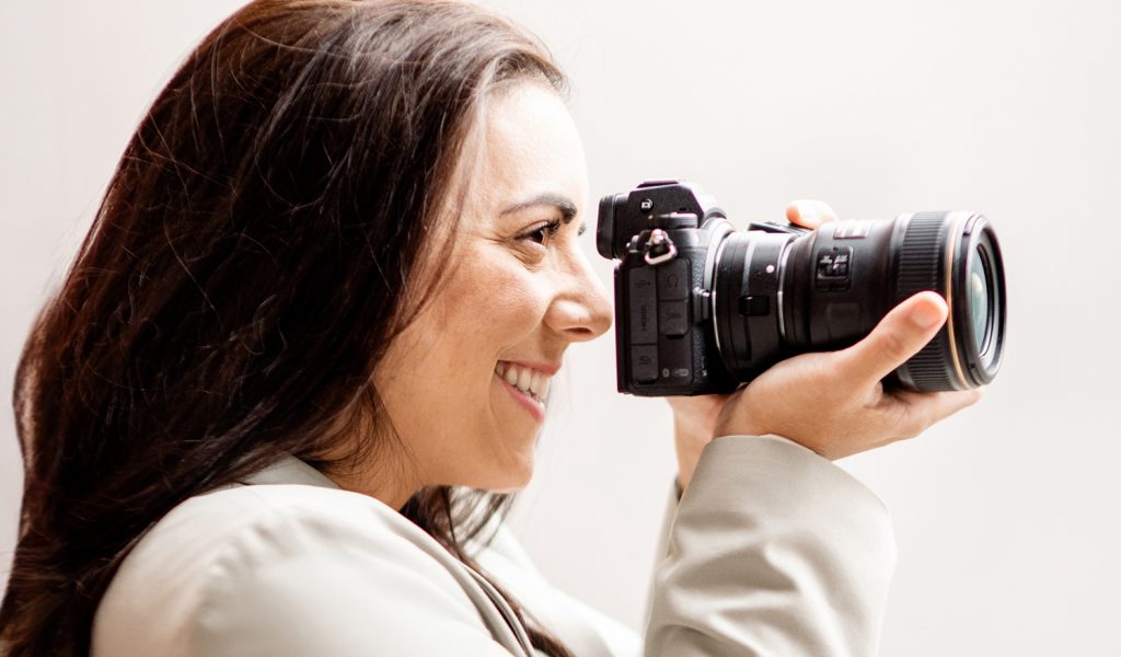 Eine Fotografin in Freiburg und Offenburg hält lächelnd eine Kamera in der Hand.